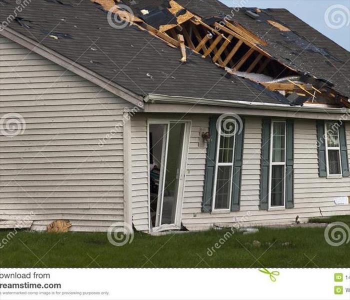 House with 4 windows and sliding glass door with part of the roof and siding tore off by wind damage